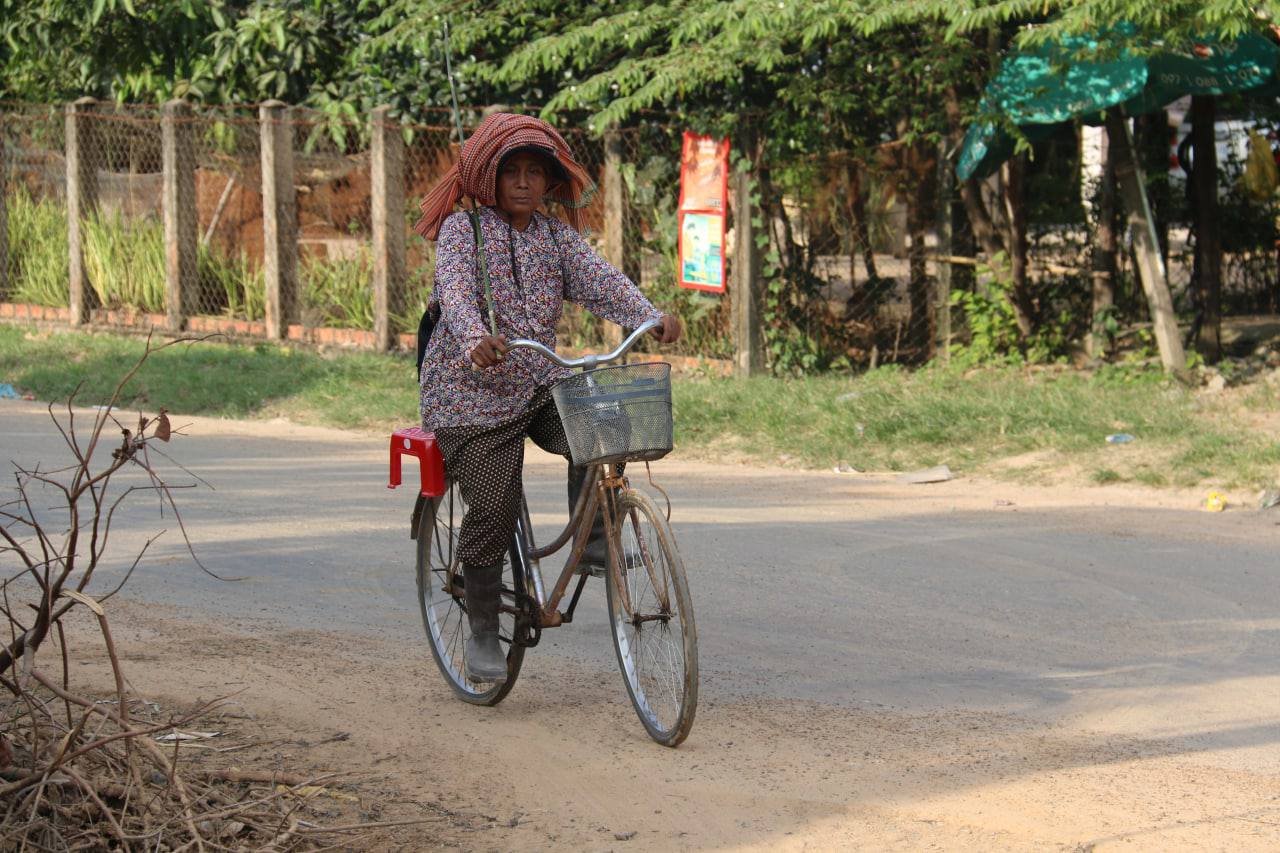 ស្ត្រីជនបទម្នាក់កំពុងជិះកង់តាមផ្លូវភូមិនៅជនបទកម្ពុជា